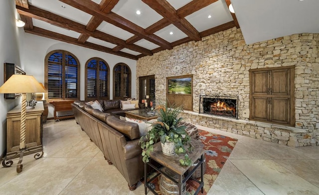 living room with beam ceiling, a stone fireplace, a towering ceiling, and coffered ceiling