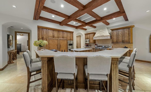 kitchen with a large island, premium range hood, a breakfast bar, and coffered ceiling