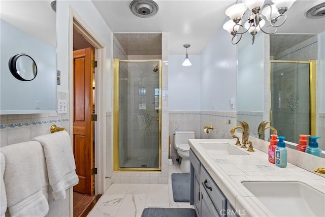 bathroom featuring an inviting chandelier, tile walls, vanity, toilet, and walk in shower