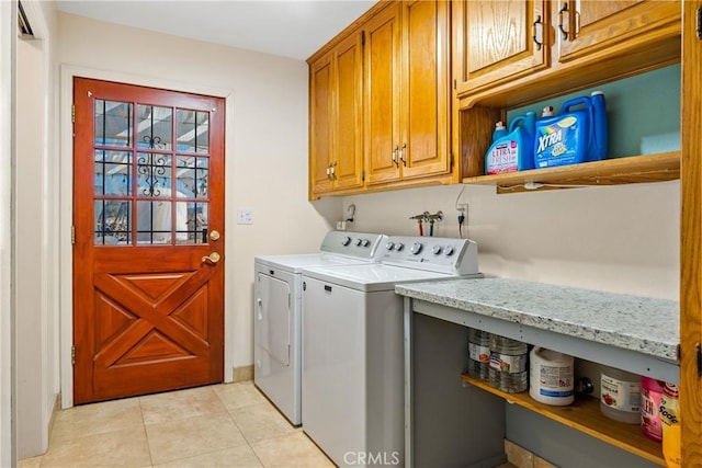 clothes washing area with independent washer and dryer, light tile patterned floors, and cabinets