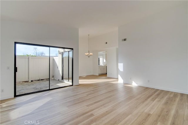 unfurnished room with a high ceiling, light hardwood / wood-style flooring, and a notable chandelier