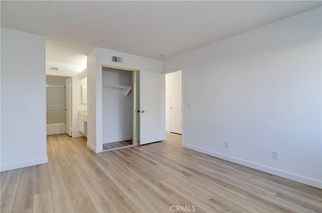 unfurnished bedroom with connected bathroom, a closet, and light wood-type flooring