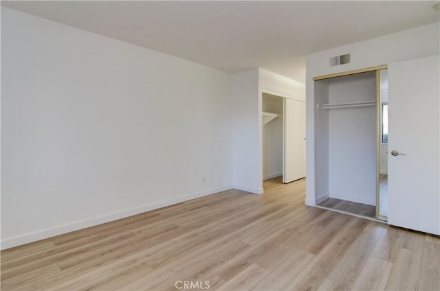 unfurnished bedroom with light wood-type flooring and a closet