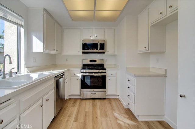 kitchen with white cabinets, light wood-type flooring, appliances with stainless steel finishes, and sink