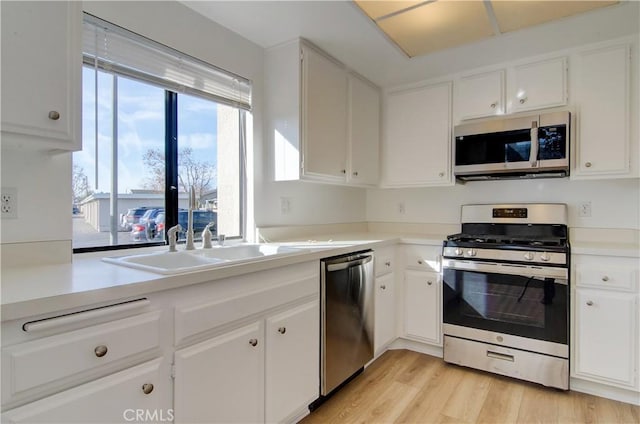 kitchen featuring white cabinets, sink, stainless steel appliances, and light hardwood / wood-style flooring