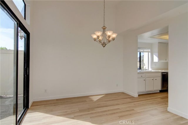 unfurnished dining area featuring a notable chandelier, light hardwood / wood-style flooring, and sink