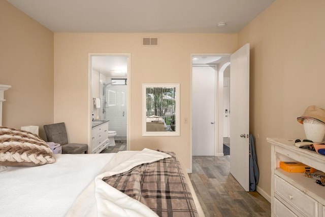 bedroom with ensuite bath and dark wood-type flooring