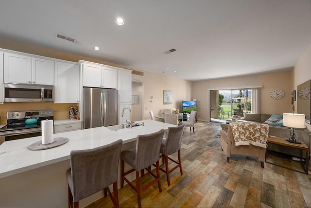 kitchen with a breakfast bar, white cabinets, sink, dark hardwood / wood-style flooring, and stainless steel appliances