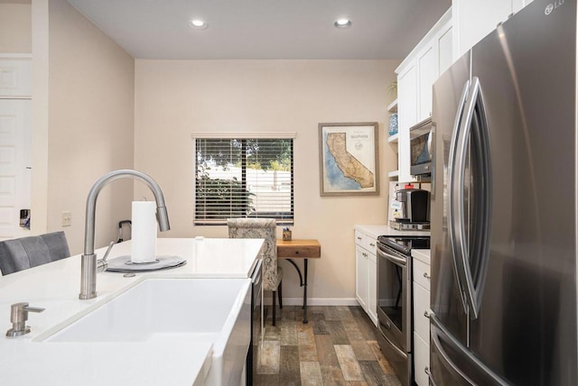 kitchen featuring appliances with stainless steel finishes, white cabinetry, dark wood-type flooring, and sink