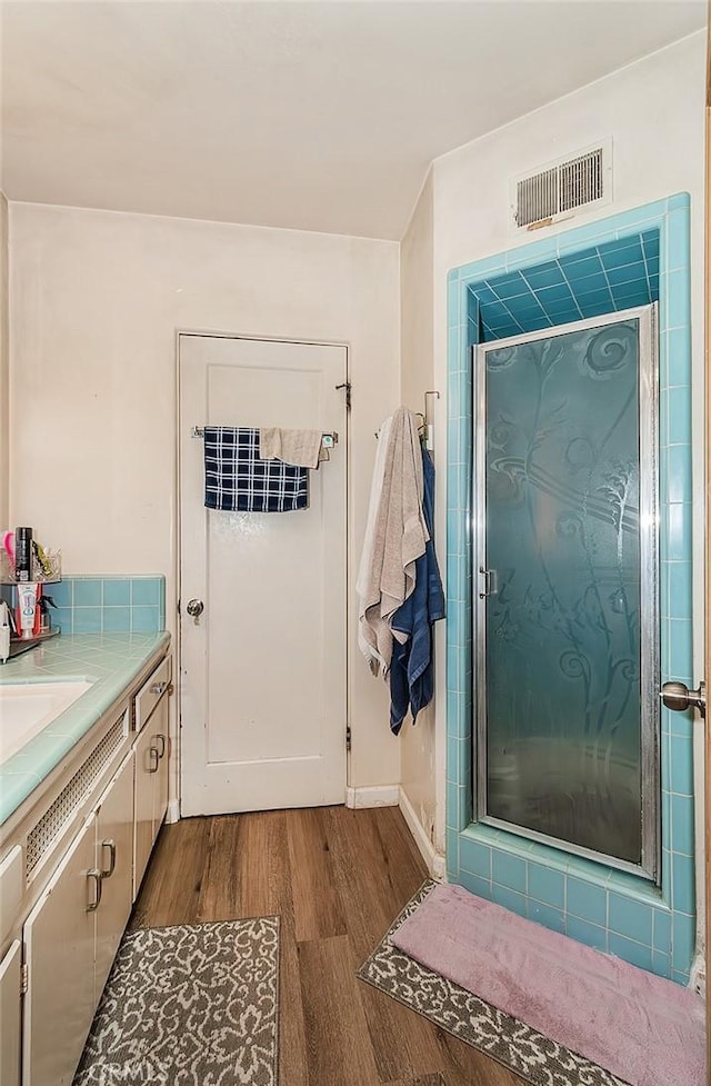 bathroom with vanity, an enclosed shower, and wood-type flooring