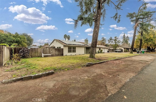 view of front of property with a front yard and solar panels