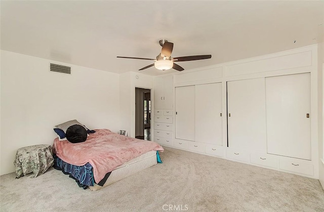 bedroom with carpet flooring, two closets, and ceiling fan