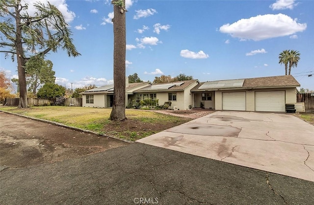 ranch-style house with solar panels, a garage, and a front yard