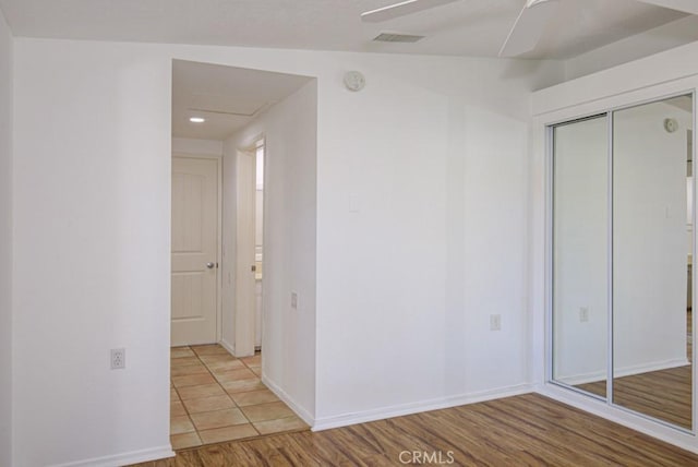 unfurnished bedroom featuring ceiling fan, light hardwood / wood-style floors, lofted ceiling, and a closet