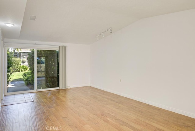 empty room with light hardwood / wood-style floors and lofted ceiling