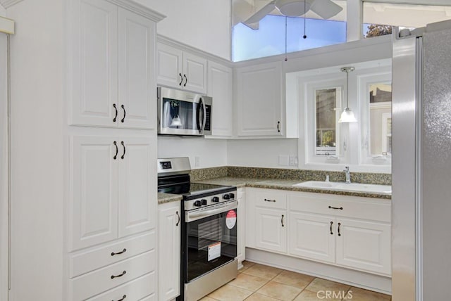 kitchen with white cabinets, sink, decorative light fixtures, light tile patterned flooring, and stainless steel appliances