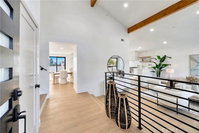 hallway with high vaulted ceiling, light hardwood / wood-style floors, and beamed ceiling