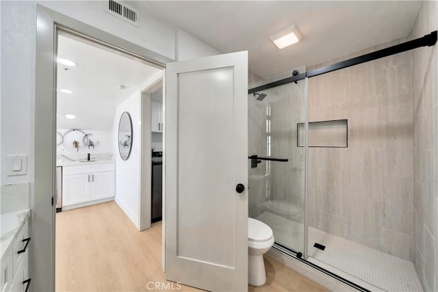 bathroom with toilet, an enclosed shower, vanity, and hardwood / wood-style floors