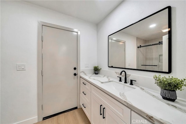 bathroom with hardwood / wood-style floors, a shower with shower door, and vanity