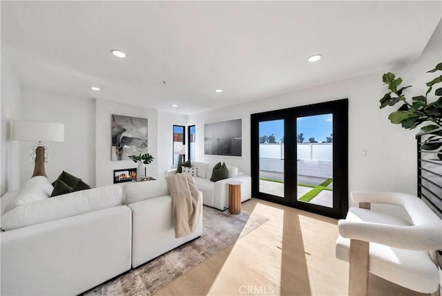 living room with french doors, light wood-type flooring, and a water view