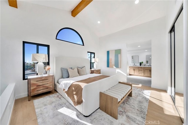 bedroom featuring beam ceiling, multiple windows, light wood-type flooring, and high vaulted ceiling