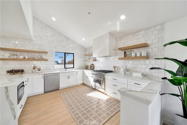 kitchen with stainless steel appliances, light stone countertops, white cabinets, light hardwood / wood-style flooring, and tasteful backsplash