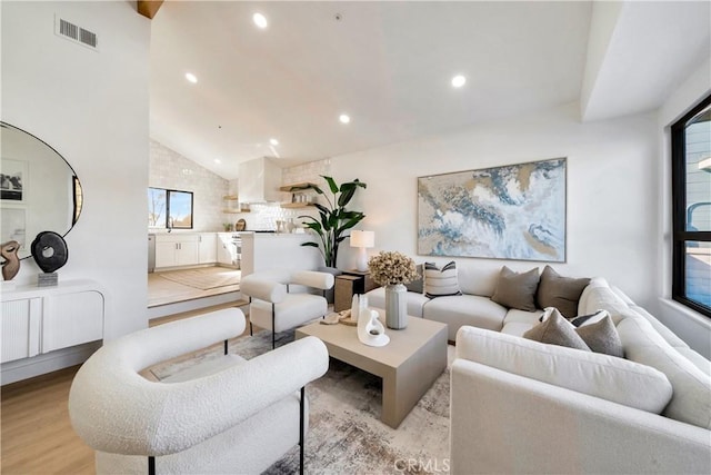 living room featuring light wood-type flooring and high vaulted ceiling