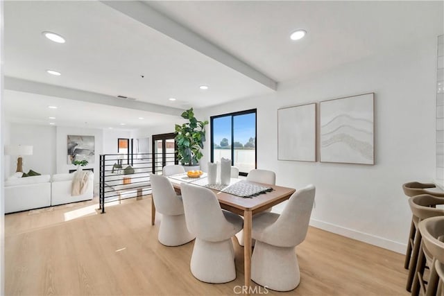 dining area featuring light hardwood / wood-style floors and beamed ceiling