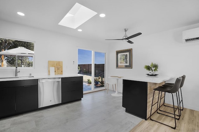 kitchen featuring an AC wall unit, a skylight, sink, ceiling fan, and stainless steel dishwasher