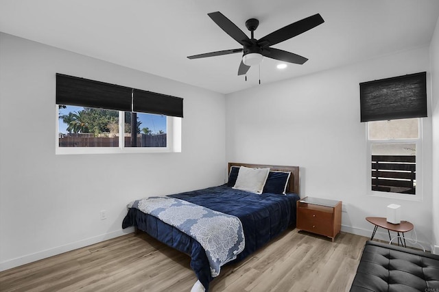 bedroom with ceiling fan, light wood-type flooring, and multiple windows