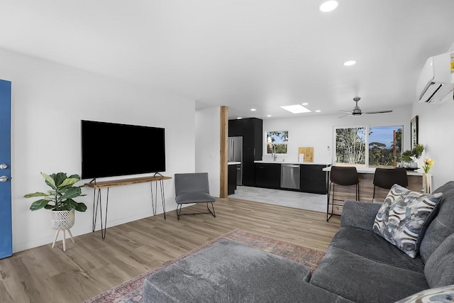 living room with ceiling fan, light hardwood / wood-style floors, and an AC wall unit