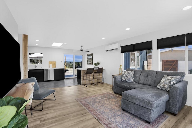 living room with ceiling fan, light hardwood / wood-style floors, sink, and a wall mounted air conditioner