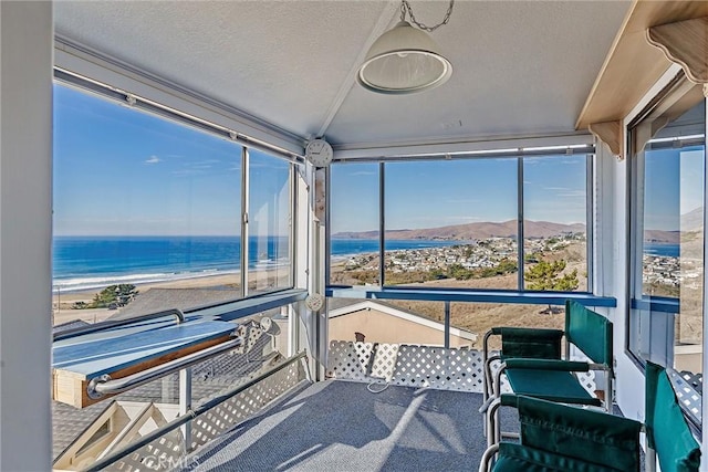 sunroom featuring a water view and a view of the beach