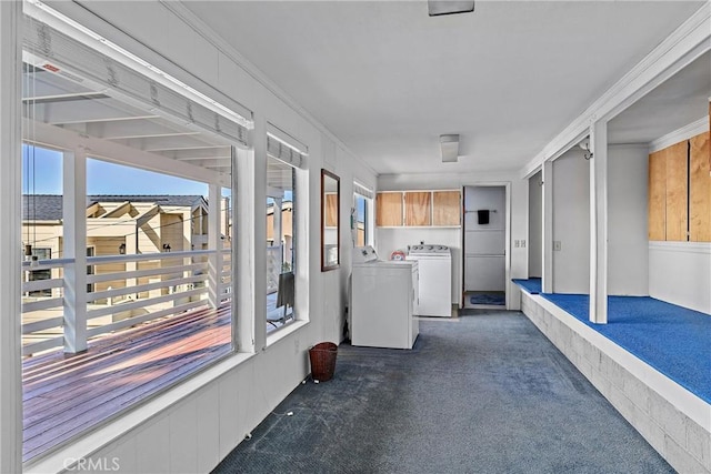 interior space featuring cabinets, washer and clothes dryer, crown molding, and dark colored carpet