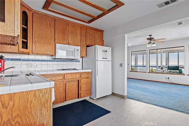 kitchen featuring white appliances, tile counters, tasteful backsplash, sink, and ceiling fan