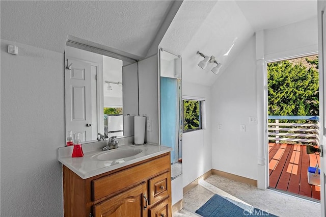 bathroom with lofted ceiling, vanity, a wealth of natural light, and a textured ceiling