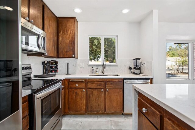 kitchen featuring light tile patterned flooring, stainless steel appliances, sink, and tasteful backsplash