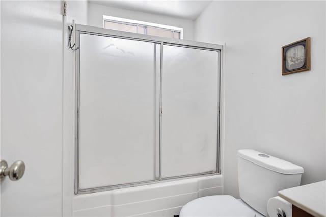 full bathroom featuring vanity, bath / shower combo with glass door, and toilet