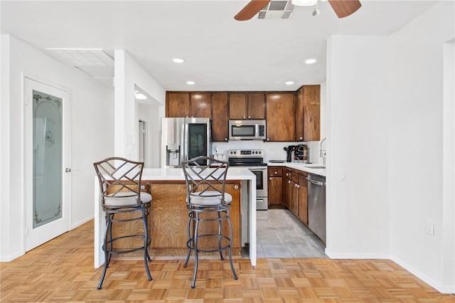 kitchen with a kitchen bar, sink, a center island, appliances with stainless steel finishes, and light parquet floors