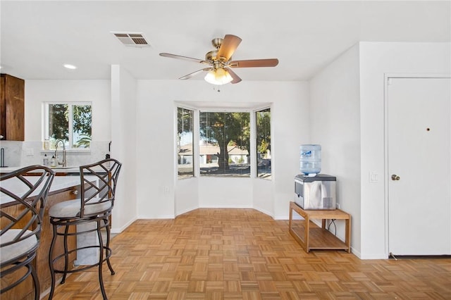 dining area featuring sink, a wealth of natural light, light parquet flooring, and ceiling fan