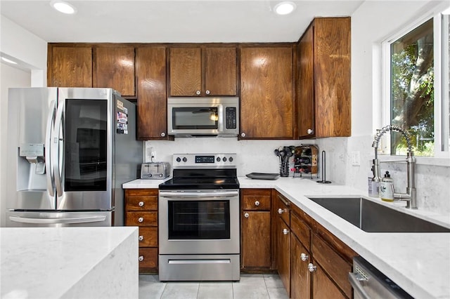 kitchen featuring appliances with stainless steel finishes, sink, light tile patterned floors, and plenty of natural light