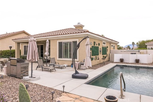 back of house with a fenced in pool and a patio