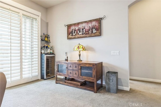 sitting room featuring bar area, light colored carpet, and beverage cooler