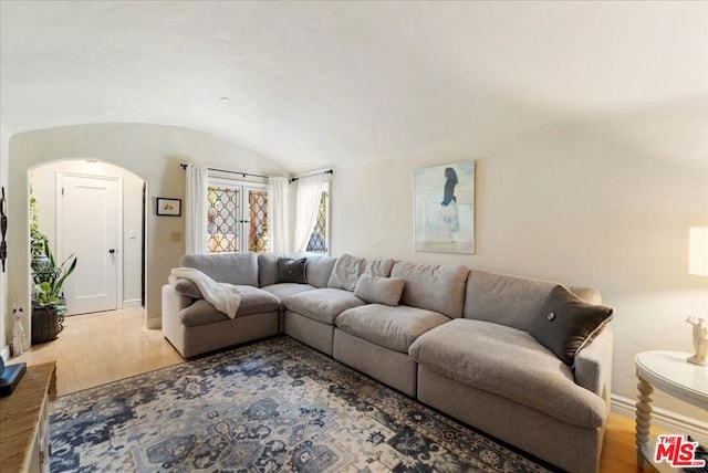 living room featuring brick ceiling, lofted ceiling, and light hardwood / wood-style floors