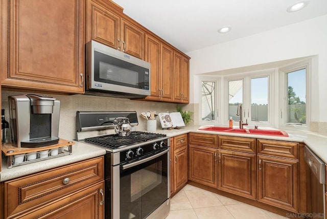 kitchen with backsplash, stainless steel appliances, sink, and light tile patterned floors