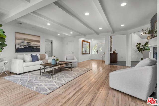 living room featuring beamed ceiling, light hardwood / wood-style floors, and a fireplace