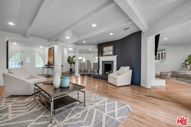 living room with a fireplace, hardwood / wood-style floors, and lofted ceiling with beams