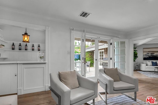 living area featuring light hardwood / wood-style floors, crown molding, and french doors