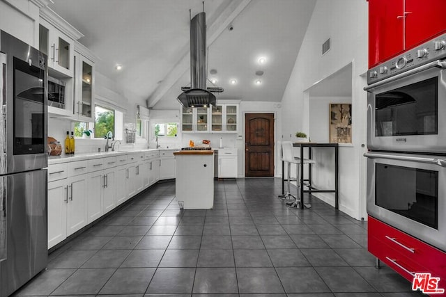 kitchen featuring beamed ceiling, a center island, stainless steel appliances, and white cabinetry