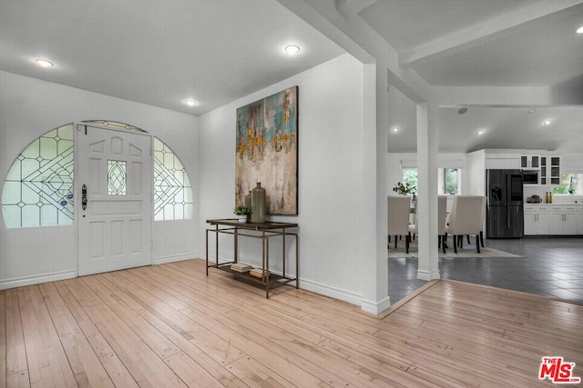 entrance foyer featuring lofted ceiling with beams and light hardwood / wood-style flooring